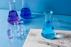 three test tubes filled with blue and purple liquid next to each other on a table