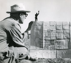 a man sitting on the ground next to a map with a person standing on top of it