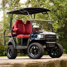 a black and red golf cart parked in front of trees