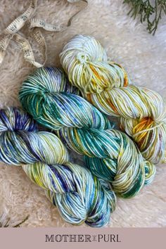 three skeins of yarn sitting on top of a pile of white furnishing