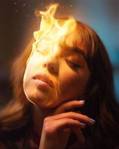 a woman's face is shown with flames coming out of her eyes and hands