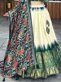 Elevate your ethnic wear collection with this beautiful off-white & green patola printed silk traditional lehenga choli. Crafted from high-quality dola silk material, this stunning ensemble features intricate patola and paithni printed work along with foil work (crush work) that adds a touch of elegance and sophistication. The off-white lehenga is paired with a green color dola silk choli and a matching dupatta, making it a perfect choice for weddings, festivals, or any special occasion.
Thi Transitional Floor-length Green Dupatta, Transitional Green Floor-length Dupatta, Off White Floor-length Traditional Wear For Navratri, Traditional White Silk Choli, Off White Traditional Wear For Navratri, Transitional Green Anarkali Set In Art Silk, White Lehenga With Traditional Patterns For Eid, Transitional White Art Silk Lehenga, Designer Green Bandhani Print Sets