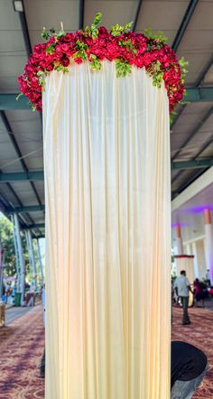 red flowers are placed on the back of a white drape at an indoor event