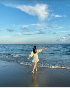 a woman standing on top of a beach next to the ocean