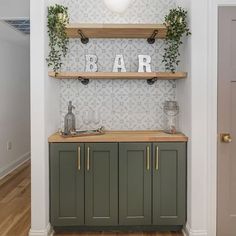 a bar with green cabinets and plants on the top shelf in a home office area