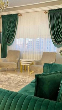 a living room filled with green velvet couches and chairs next to a chandelier