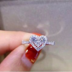 someone holding a heart shaped diamond ring in their hand