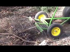 a green and yellow lawn mower sitting on top of dry grass in the woods