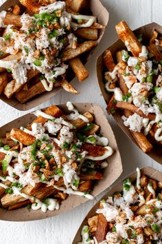 four baskets filled with french fries covered in toppings