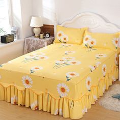 a bed with yellow bedspread and white flowers on it next to a window