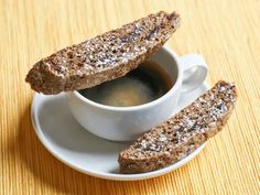 two cookies are sitting on a saucer next to a cup of espresso