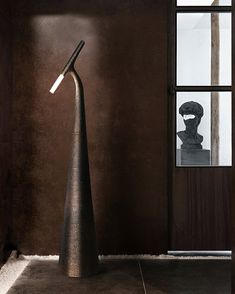 a tall metal lamp sitting on top of a floor next to a window in a room