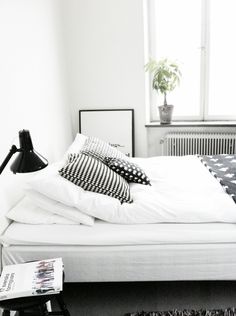 a black and white photo of a bed with two pillows on top of it next to a window