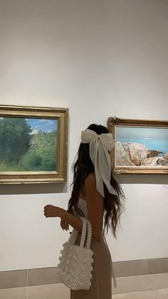 a woman is looking at paintings on the wall