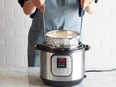 a person in an apron is stirring something into the pot on top of the pressure cooker