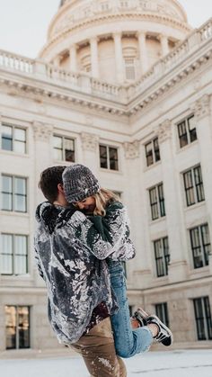 a man and woman kissing in front of a large building with a dome on top