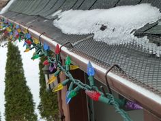 christmas lights are hanging from the roof of a house