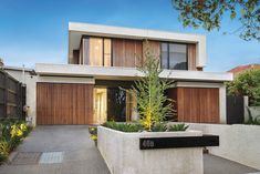 a modern house with wooden doors and windows on the front side, surrounded by greenery