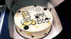 a birthday cake with the simpsons character on it is sitting in a cardboard box that says mmm beer