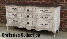 an old dresser with black and white paint on it's drawers is shown in front of a brick wall