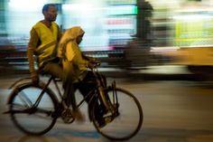 two people riding on the back of a bike