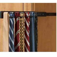 several ties are hanging on a tie rack in front of a wooden door with metal bars