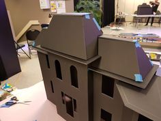 a model of a house is shown in the middle of a room with people working on it