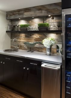 a kitchen with stainless steel appliances and wooden shelves filled with wine bottles, glasses and vases