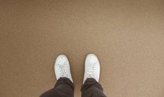 a person wearing white shoes standing on top of a brown carpet