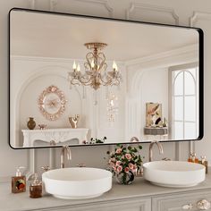 a bathroom with two sinks and a large mirror over it's counter top that has a chandelier hanging from the ceiling