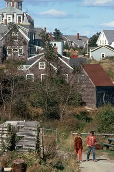 two people walking down a path in front of houses