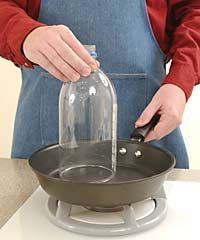 a person in an apron is using a bottle to stir something on the stove top