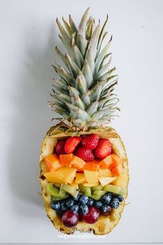 a pineapple filled with fruit on top of a white table