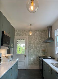 a kitchen with a light hanging over the stove and counter top next to an open door