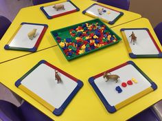 children's play area with toy animals and colored plastic trays on yellow table