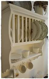 a white shelf filled with plates and cups on top of a wooden shelf next to a wall