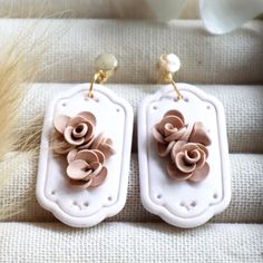 two white earrings with pink flowers on them