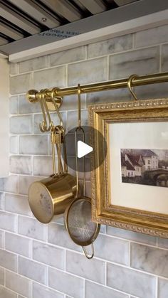 an old photo hangs on the wall next to a pot rack with two pans hanging from it