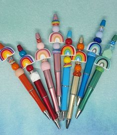 a bunch of pens that are sitting on a blue tablecloth with rainbows in the background