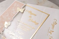 two wedding cards with gold and white designs on the front one has a butterfly design