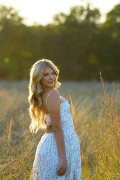 a beautiful young woman standing in tall grass