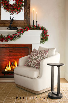 a white chair sitting in front of a fire place next to a christmas wreath on the wall