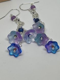 These are lovely dainty blue/purple flower drop earrings made with gold toned fish hook wires. These are handmade and you will love to either own or gift them to someone special. Made with silver plated wires. We make these with quality materials, no acrylics nor plastics.  And we ship for free! Whimsical Blue Jewelry With Flower Charm, Blue Whimsical Dangle Flower Earrings, Whimsical Blue Dangle Flower Earrings, Blue Flower-shaped Sterling Silver Earrings, Handmade Blue Whimsical Flower Earrings, Whimsical Handmade Blue Flower Earrings, Nickel-free Blue Flower Earrings, Blue Dangle Flower Earrings, Purple Flower Earrings With Ear Wire For Gift