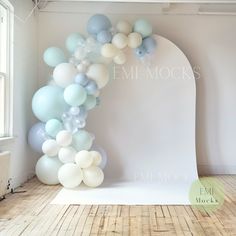 an arch made out of balloons is displayed in the room with white walls and wood flooring