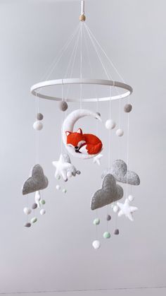 a baby crib mobile with a red fox sleeping on it's back in the sky