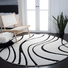 a black and white rug in the corner of a room with a chair, potted plant and door