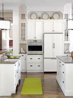 a kitchen with white cabinets and green rugs on the hardwood floor, along with an area rug in front of the stove