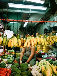 a woman sitting in front of a table filled with lots of fruits and vegetables