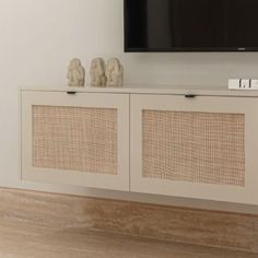 a flat screen tv mounted to the side of a white cabinet with wicker doors