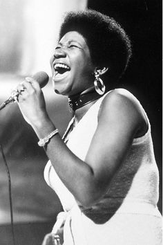 a black and white photo of a woman singing into a microphone